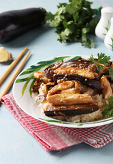 Chicken with eggplant in a spicy sauce. Delicious Asian homemade snack on light blue table.