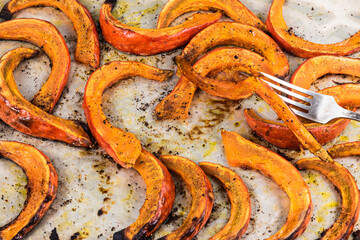 Baked pumpkin slices on baking paper, close-up