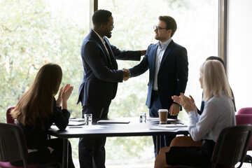 Happy African American business leader shaking hands with promoted employee. Boss hiring new team...