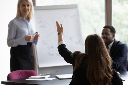 Mature Middle Aged Mentor, Corporate Teacher, Presenter Giving Seminar, Answering Questions From Audience On Business Training Meeting. Employee, Intern, Student Raising Hand For Asking Coach