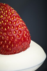Perfectly ripe strawberries with cream. Macro photography. Isolated on dark background with reflection. In appearance Reminiscent of Santa's hat.