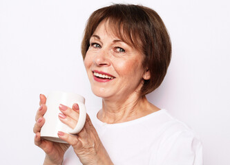 Old excited lady smiling laughing, holding cup drinking coffee, tea, beverage on white background