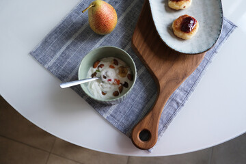 Morning breakfast with cheesecake, yoghurt and pea in the corner of table on a napkin. Sirniki is Russian cheesecake. High quality photo. Free space for text.