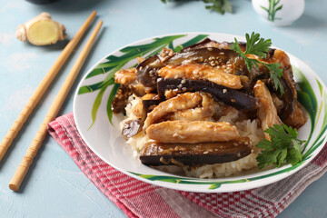Chicken with eggplant in a spicy sauce. Delicious Asian homemade snack on light blue table.