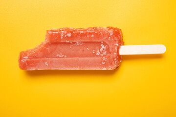 top view red popsicle with a bite on a yellow background