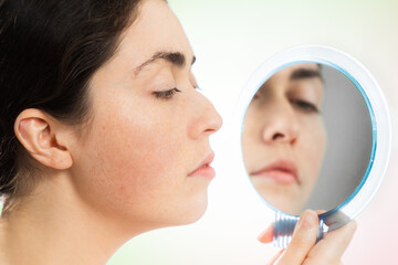 Aesthetic medicine. Profile portrait of a young Caucasian woman looking at her humpback nose in the...