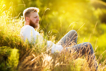 Man with a beard lies on a summer meadow