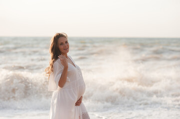 Fototapeta na wymiar Beautiful laughing pregnant woman wear white dress posing over sea at background closeup. Healthy lifestyle. Motherhood. Maternity. Happiness.