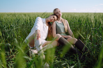 Portrait of two fair-haired girls in fashionable and stylish clothes, against the background of a field. Nature, vacation, relax and lifestyle. Fashion concept.