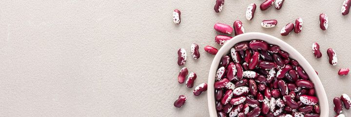 Legumes in bowl and scattered in the background, red beans in a plate banner, top view, copy space