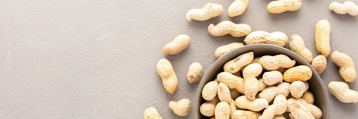 Legumes in bowl and scattered in the background, peanuts in a plate banner, top view, copy space