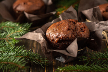 Delicious chocolate muffins on dark wooden background among fir branches, Merry Christmas and Happy New Year