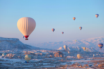 Hot air balloons flying over the famous tourist place Cappadocia at winter time