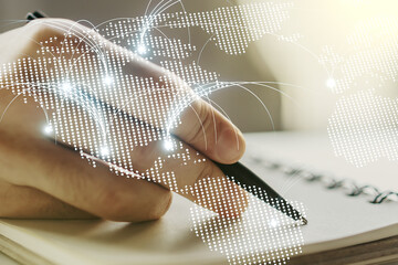 Double exposure of abstract digital world map with connections and man hand writing in notebook on background, research and strategy concept