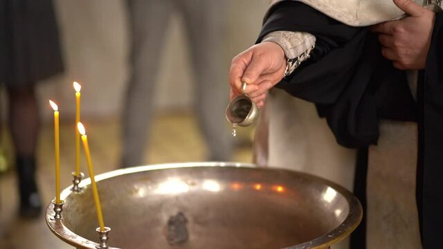 the priest pours holy water into the baptismal font. 