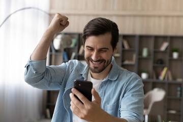 Overjoyed sincere handsome happy young man looking at smartphone screen, celebrating getting amazing unbelievable news, online lottery giveaway win, victory notification, internet success concept.