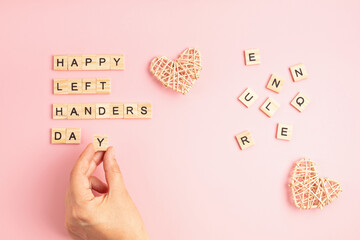 Text happy left handers day written with wooden letters and heart over pink background