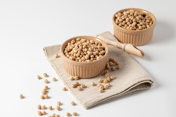 dry chickpeas, in a ceramic dish on a white table, top-side view