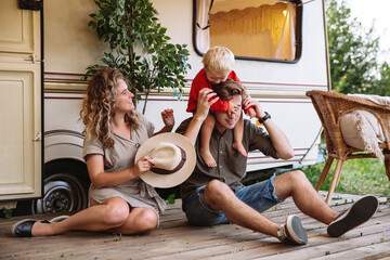 Family trip, caravan camping lifestyle and recreation: young parents relaxing with small son at...