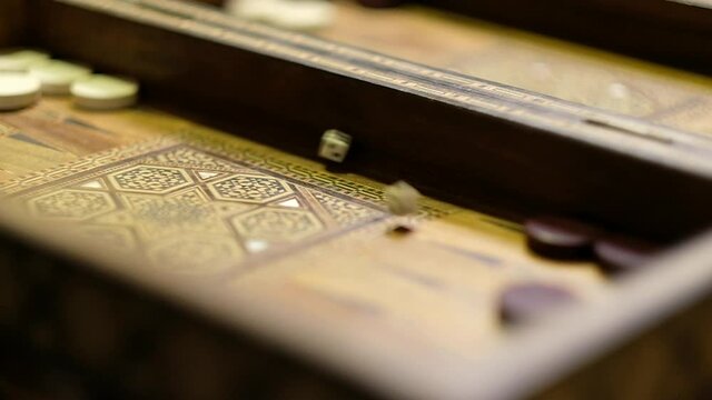 An extreme shallow depth of field, slow motion clip of a Backgammon cube throwing game.