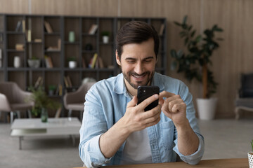 Happy addicted to modern digital technologies man using smartphone apps, enjoying distant...