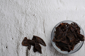 Jerky meat on a concrete background. Dried beef. Glassware. Copy space. Close-up. Flat lay.
