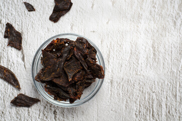 Jerky meat on a concrete background. Dried beef. Glassware. Copy space. Close-up. Flat lay.