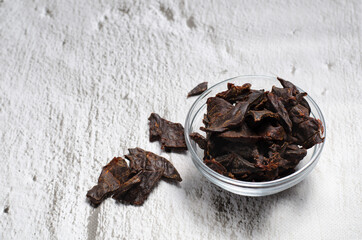Jerky meat on a concrete background. Dried beef. Glassware. Copy space. Close-up. Flat lay.