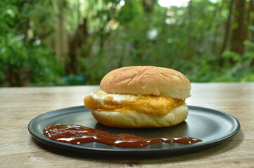 fried fish hamburger stuffed mayonnaise sauce with ketchup on plate