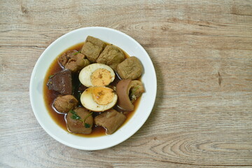 boiled half cut egg with tofu in herb brown soup and pork leg on plate