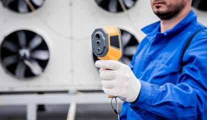 Technician uses a thermal imaging infrared thermometer to check the condensing unit heat exchanger.