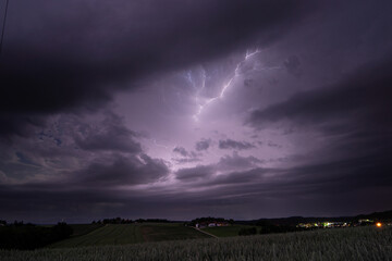 Wolken-Wolken blitz eines Sommerunwetters im S&uuml;den von Bayern. Das Motive zeigt ein Getreidefeld und &uuml;berwiegend den Himmel.
