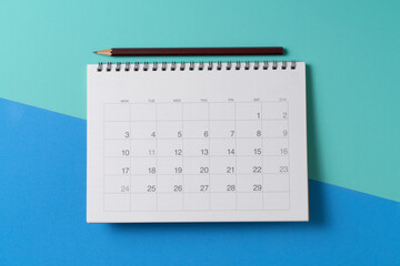close up of calendar and pencii on the green and blue table background, planning for business meeting or travel planning concept - obrazy, fototapety, plakaty