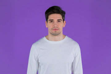 Portrait of handsome man in white wear looking to camera. Guy in studio on bright purple background.