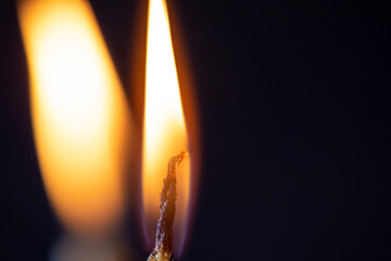 The bright flame of a dying candle on a dark background close-up.