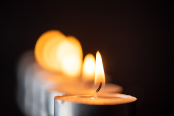 The bright flame of a dying candle on a dark background close-up.