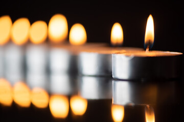The bright flame of a dying candle on a dark background close-up.