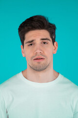 Fototapeta premium Frustrated european man over teal wall background. Guy is tired, bored of work or studying, he disappointed, helpless