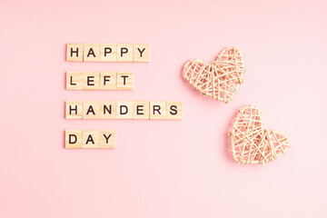 Text happy left handers day written with wooden letters and heart over pink background
