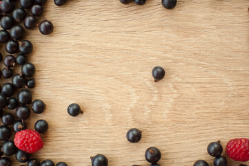 Fresh organic berries, black currant and raspberry, on wooden table. Raw food and healthy eating, berry diet. Ingredients for smoothies. Frame, copy space for inscription