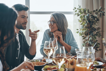 Happy multi-generation family communicating and smiling while having dinner together