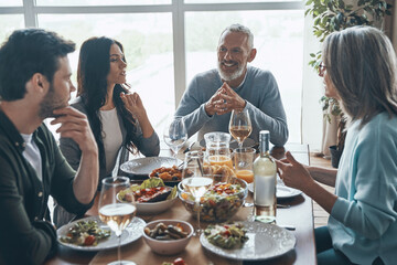 Happy multi-generation family communicating and smiling while having dinner together