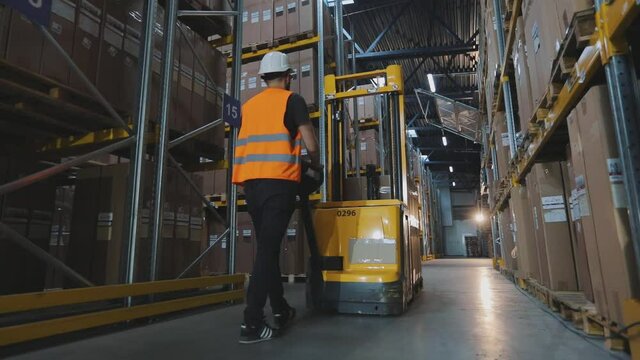A worker transports a load on an electric hydraulic forklift. Large modern warehouse. Modern special equipment in stock