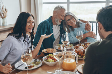 Happy multi-generation family communicating and smiling while having dinner together