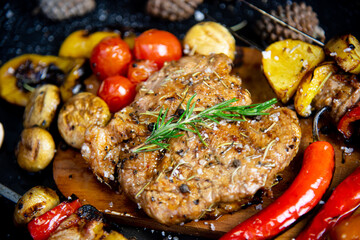 Steak on a wooden cutting board and black background sprinkled with salt and pepper.