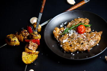 Steak on the plate and black background sprinkled with salt and pepper.
