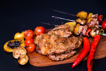 Steak on a wooden cutting board and black background sprinkled with salt and pepper.
