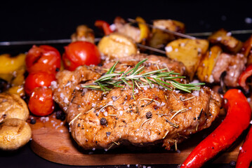 Steak on a wooden cutting board and black background sprinkled with salt and pepper.