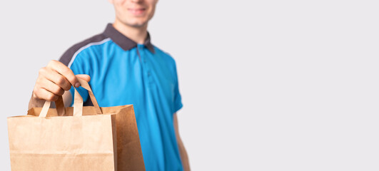 Delivery man in a blue polo shirt holding a package carton bag with handless pulling it forward and...