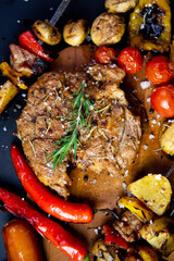 Steak on a wooden cutting board and black background sprinkled with salt and pepper.